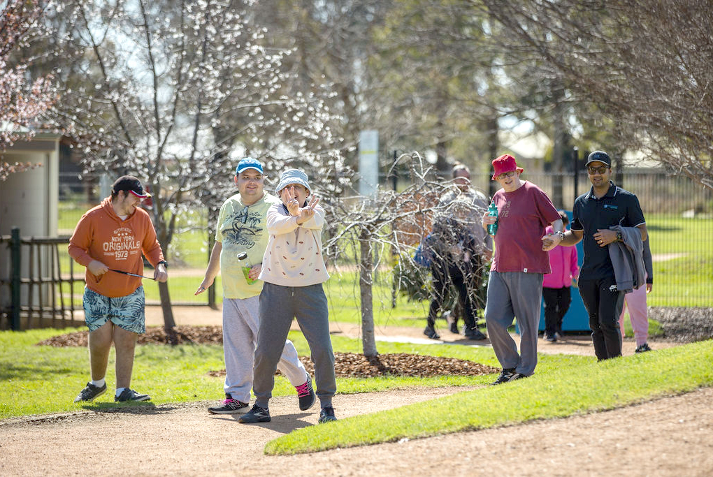 A group of people walking and enjoying a sunny day in a park.